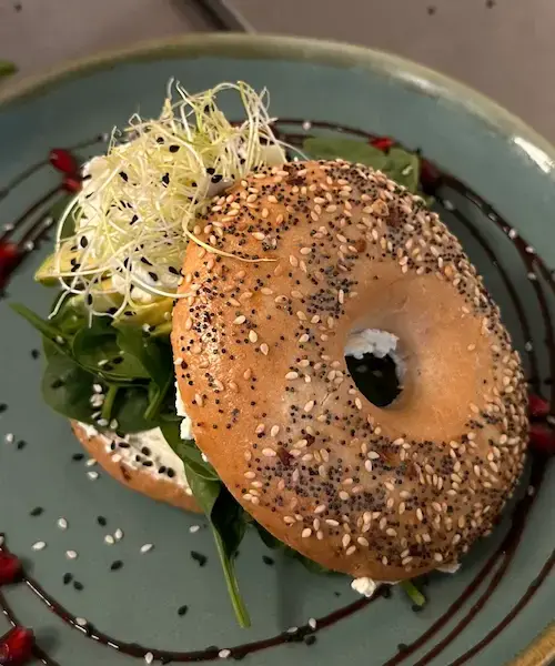 Wolfstor Bagel mit Frischkäse, Babyspinat, Avocado, Knoblauchsprossen, Balsamicocreme und Sesam