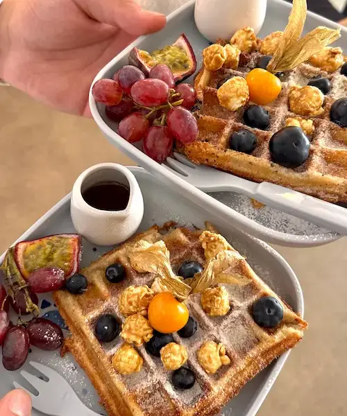 Zwei Portionen Dicker Turm, belgische Waffel mit Blaubeeren, Trauben, Popcorn, Puderzucker und Ahornsirup